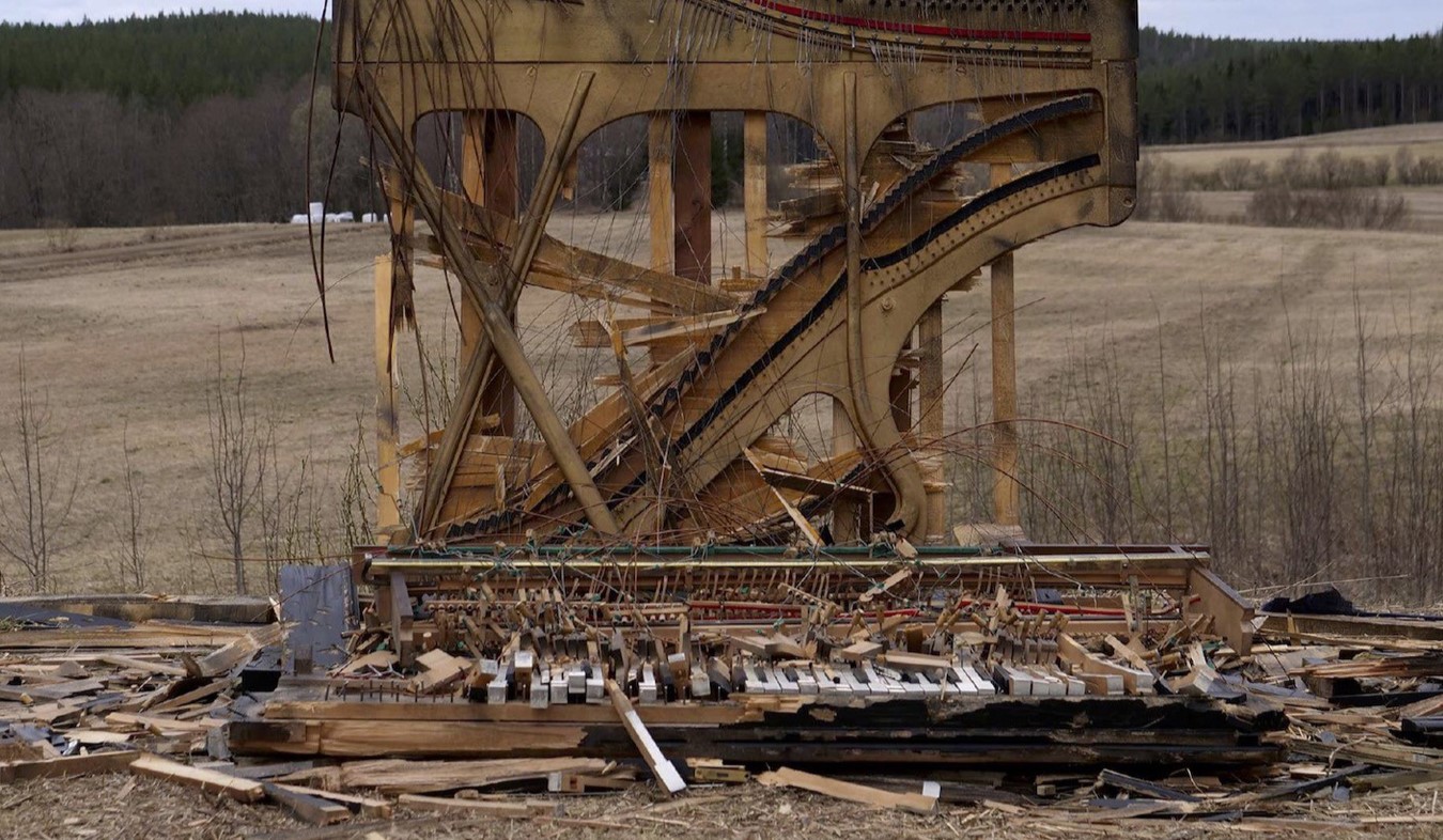 Rikkoutunut piano peltomaisemassa.